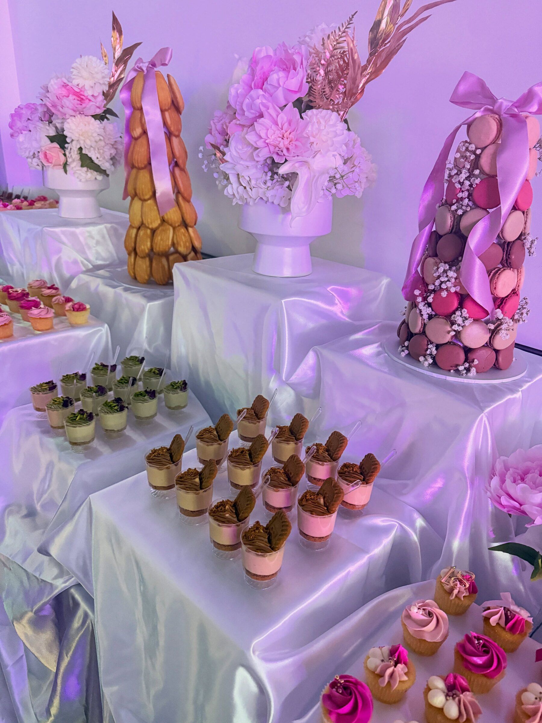 A pink dessert table with macaron towers, florals and satin draping