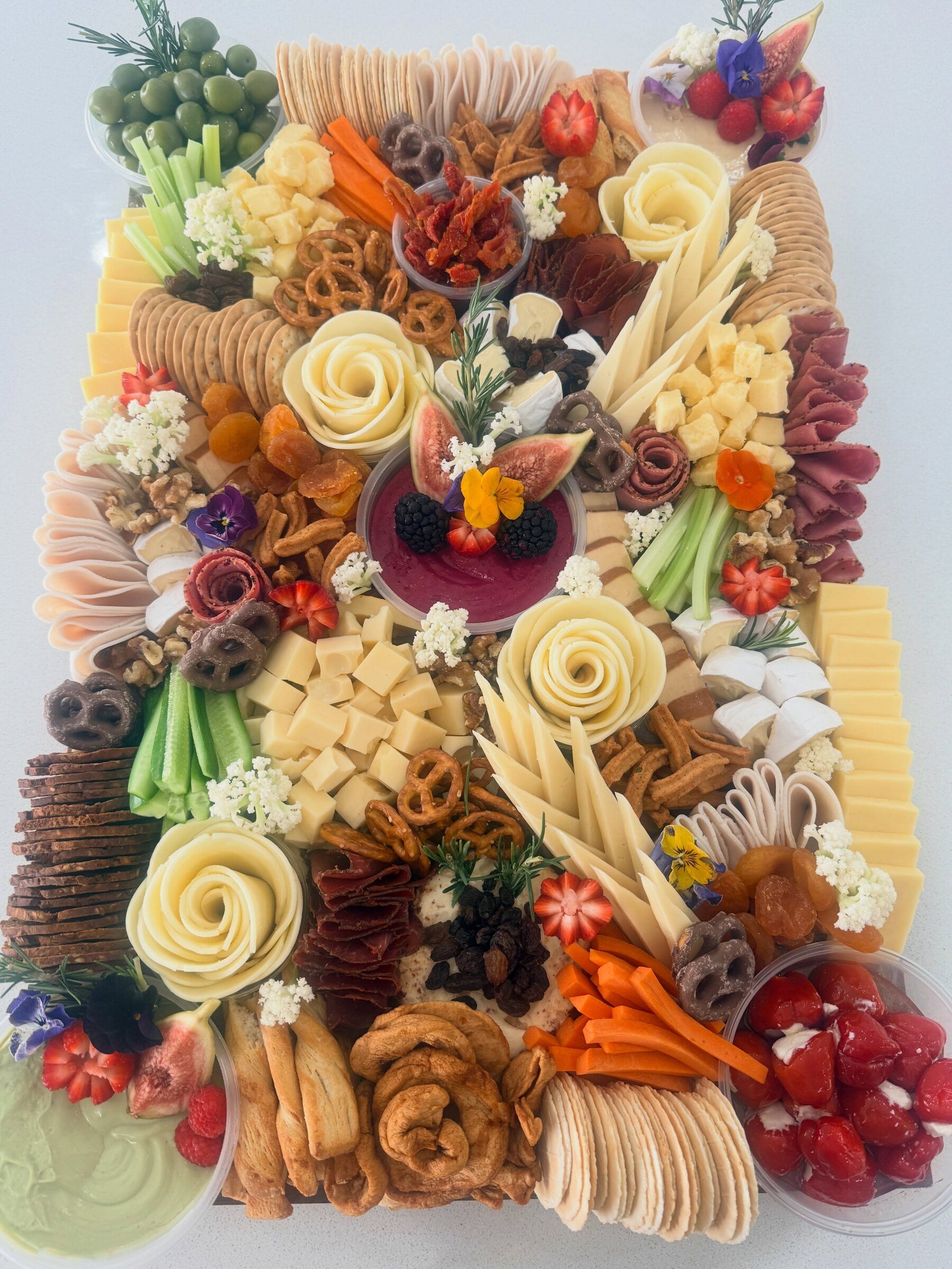 A deluxe grazing board with hand-rolled cheese roses, crackers, cold cuts and fresh fruit