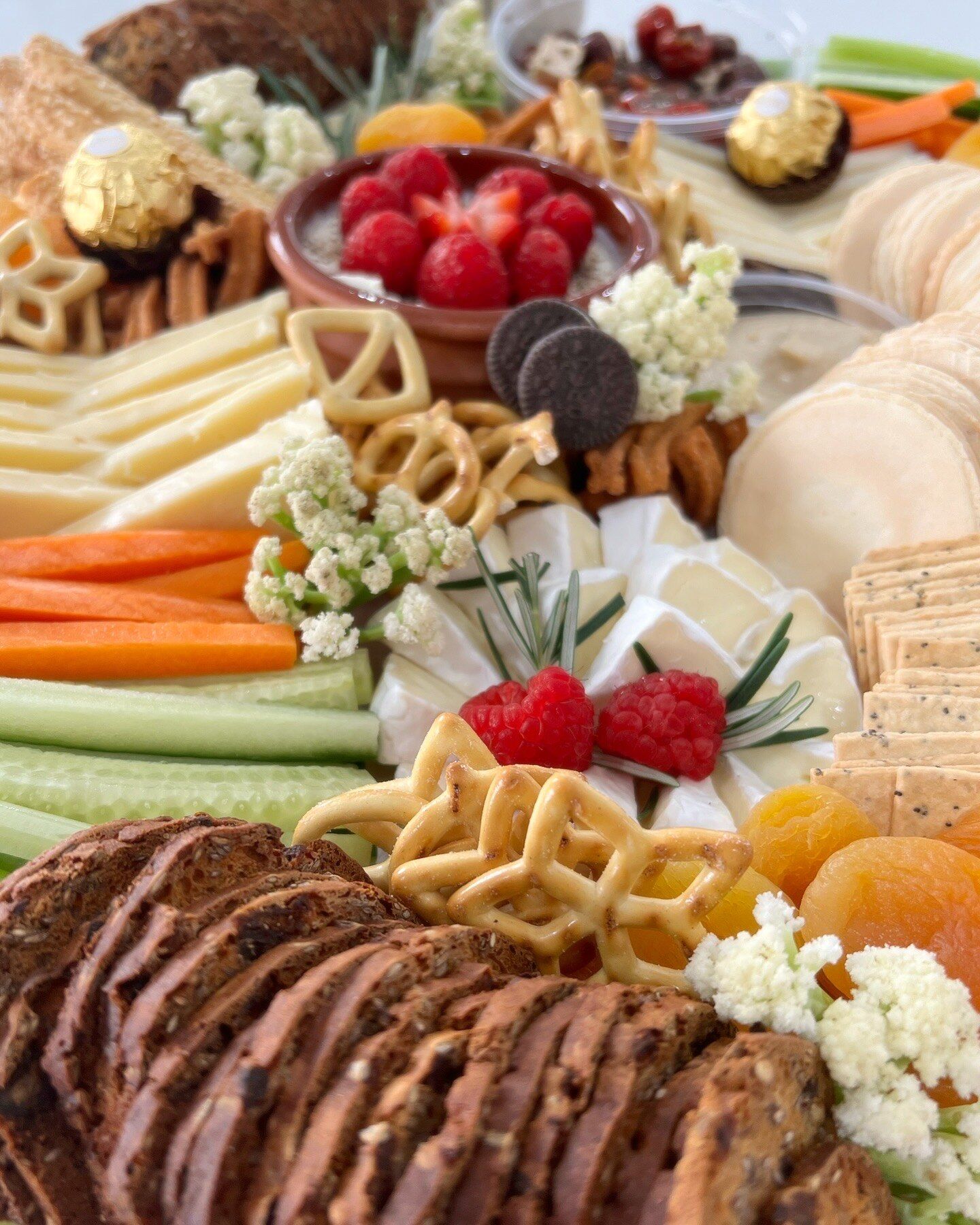 A close-up of a grazing board with cheese, crackers and fresh berries