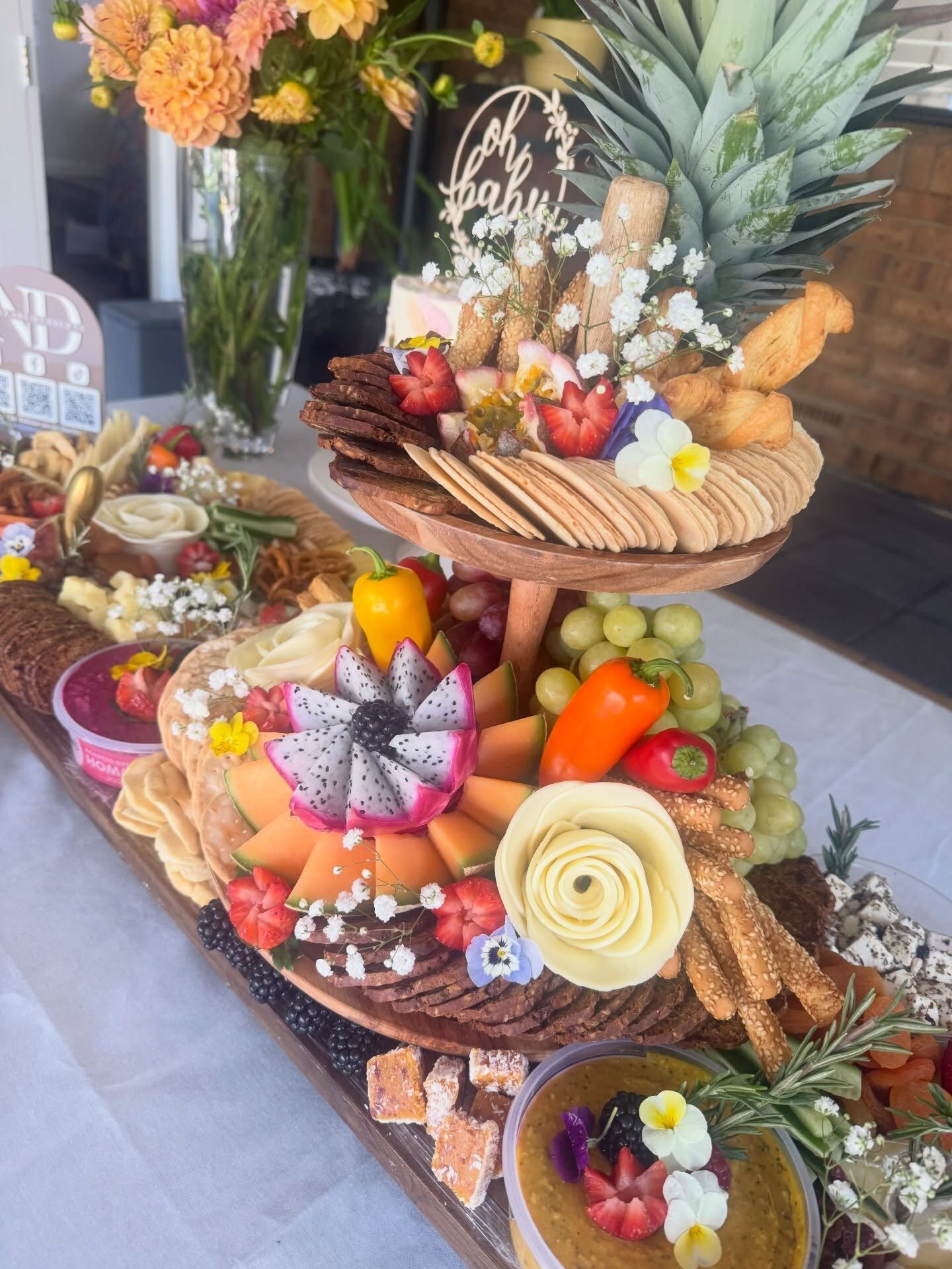 A grazing board with a carved fruit tier, cheese roses and edible flowers